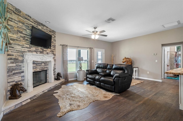 living area with ceiling fan, a fireplace, visible vents, baseboards, and dark wood finished floors