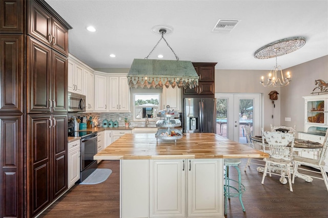 kitchen with stainless steel appliances, a center island, butcher block countertops, and french doors