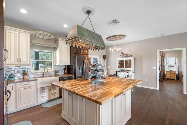 kitchen with sink, butcher block countertops, a center island, hanging light fixtures, and stainless steel appliances