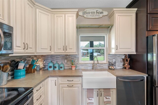 kitchen with sink, backsplash, stainless steel appliances, and cream cabinetry