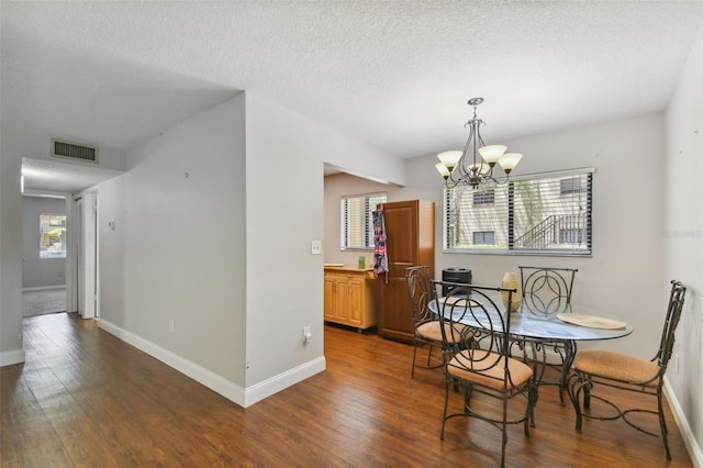 dining space with a notable chandelier, dark hardwood / wood-style flooring, and a textured ceiling