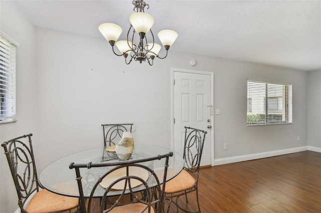 dining space with dark wood-type flooring, a textured ceiling, and a notable chandelier