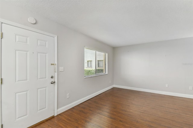 entrance foyer featuring a textured ceiling, dark wood-style flooring, and baseboards