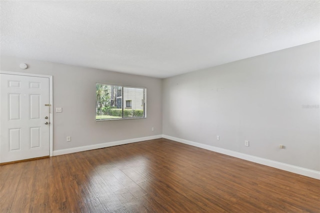 unfurnished room with dark hardwood / wood-style flooring and a textured ceiling