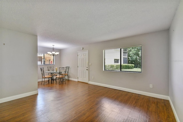 living room featuring an inviting chandelier, dark hardwood / wood-style floors, and a textured ceiling