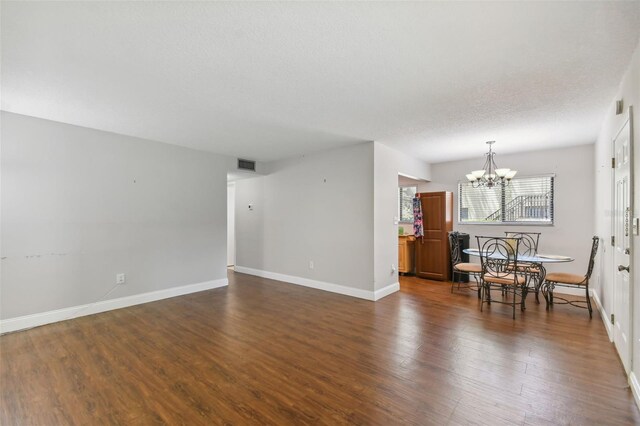 living room with a textured ceiling, a chandelier, and dark wood-type flooring