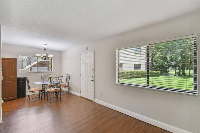 dining space featuring a textured ceiling, an inviting chandelier, wood finished floors, and baseboards