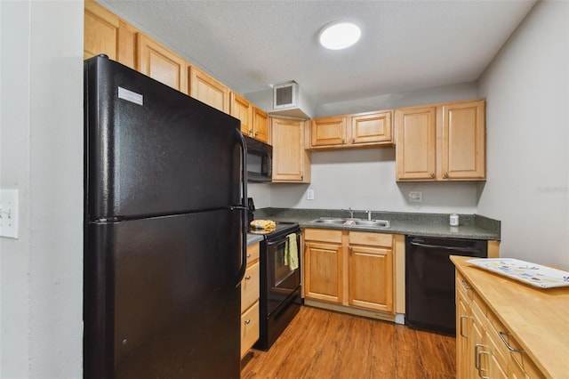 kitchen featuring wood-type flooring, black appliances, light brown cabinets, and sink