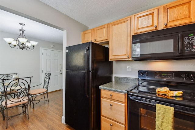 kitchen featuring a notable chandelier, black appliances, pendant lighting, light wood-type flooring, and a textured ceiling