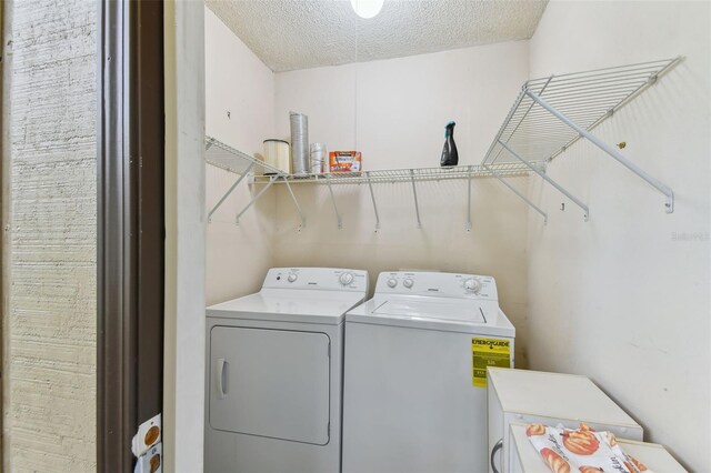 clothes washing area with washer and clothes dryer and a textured ceiling