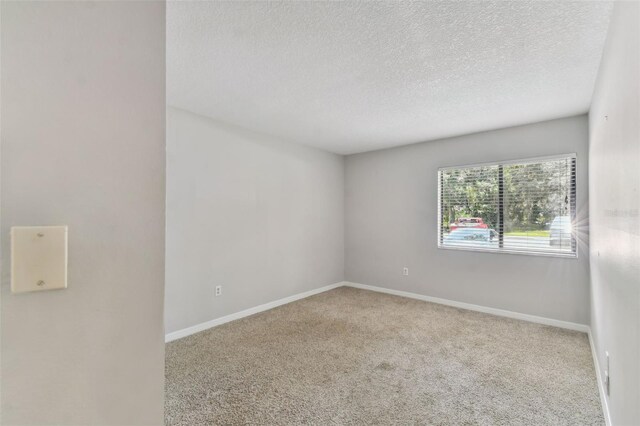 empty room with light carpet and a textured ceiling