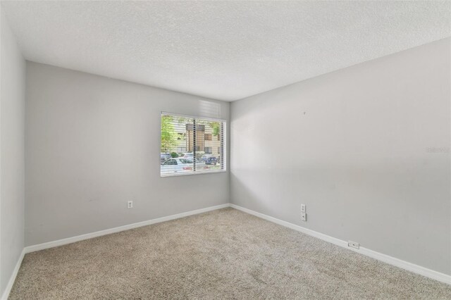 unfurnished room with carpet and a textured ceiling