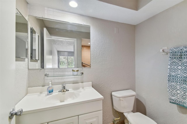 half bath with toilet, vanity, and a textured wall