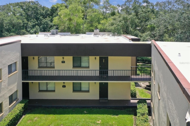 back of house featuring cooling unit, a lawn, and stucco siding