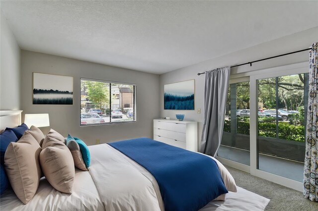 bedroom with access to exterior, multiple windows, a textured ceiling, and carpet flooring