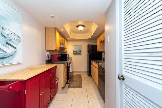 kitchen with black appliances, butcher block countertops, light tile patterned floors, and a tray ceiling