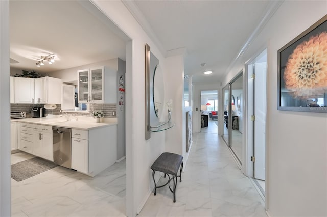 kitchen featuring crown molding, decorative backsplash, stainless steel dishwasher, and white cabinets