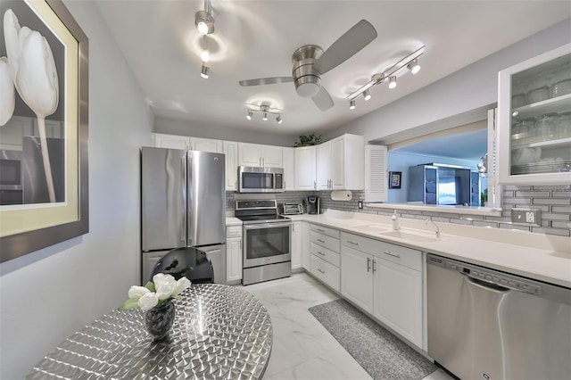 kitchen with backsplash, appliances with stainless steel finishes, sink, and white cabinets