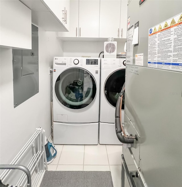 clothes washing area featuring electric panel, cabinets, washing machine and dryer, heating unit, and light tile patterned flooring