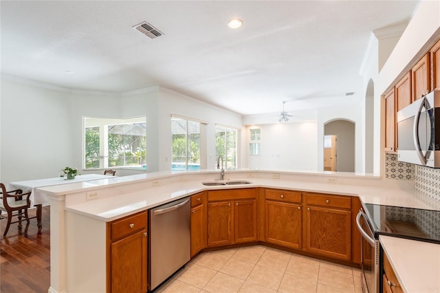 kitchen featuring stainless steel appliances, sink, kitchen peninsula, light tile patterned floors, and crown molding