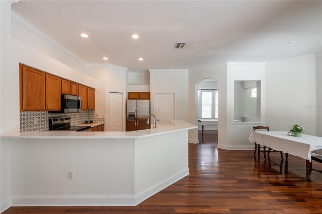 kitchen with stainless steel appliances, crown molding, kitchen peninsula, backsplash, and dark wood-type flooring