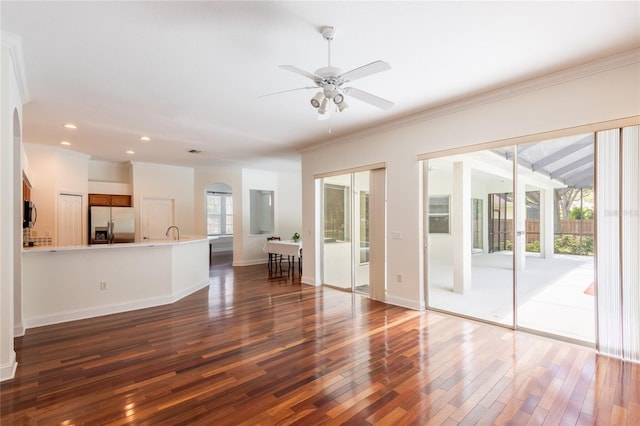 unfurnished living room with wood-type flooring, a healthy amount of sunlight, and ceiling fan