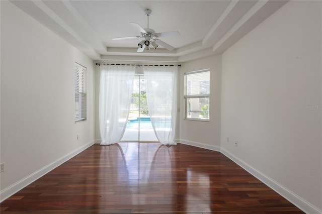 empty room featuring ceiling fan, hardwood / wood-style floors, and a tray ceiling