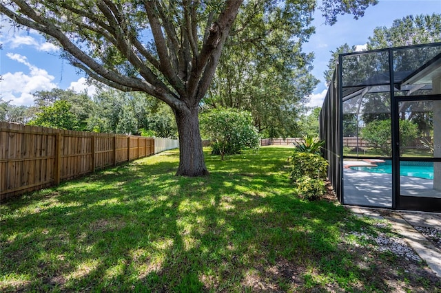 view of yard with a fenced in pool and glass enclosure