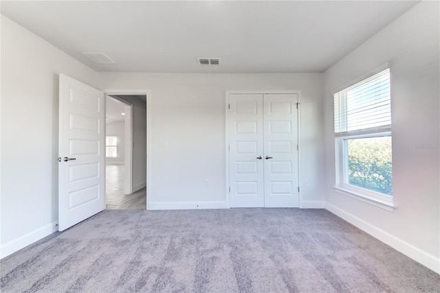 unfurnished bedroom with light carpet and a closet