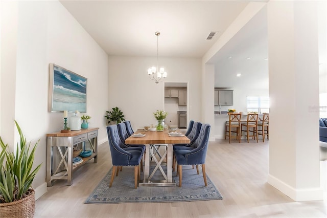 dining area featuring light hardwood / wood-style floors and an inviting chandelier