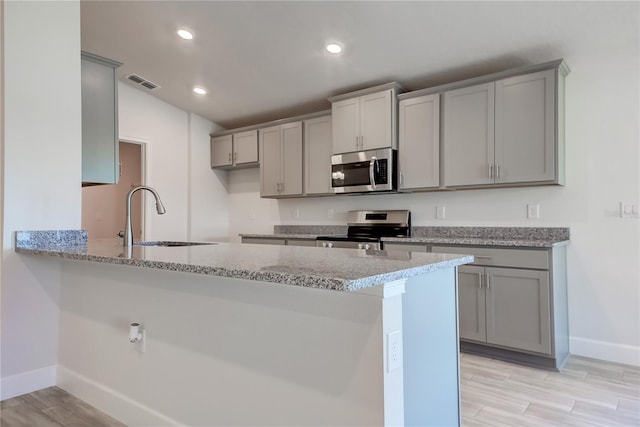 kitchen with appliances with stainless steel finishes, gray cabinets, and sink