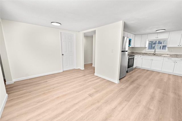 kitchen featuring sink, appliances with stainless steel finishes, light stone countertops, light hardwood / wood-style floors, and white cabinets