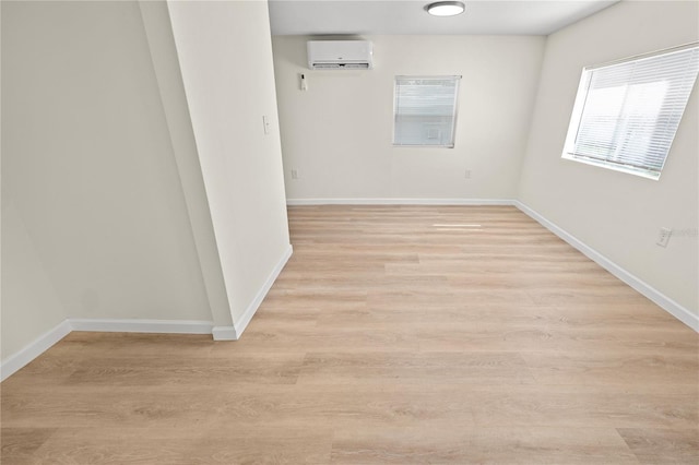 spare room with a wall mounted air conditioner and light hardwood / wood-style floors