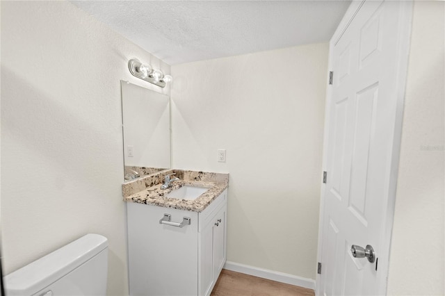 bathroom with vanity, a textured ceiling, wood-type flooring, and toilet