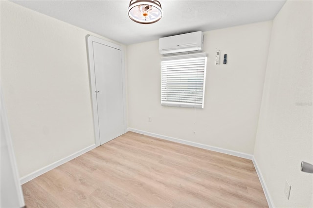 unfurnished room featuring a wall mounted AC and light wood-type flooring