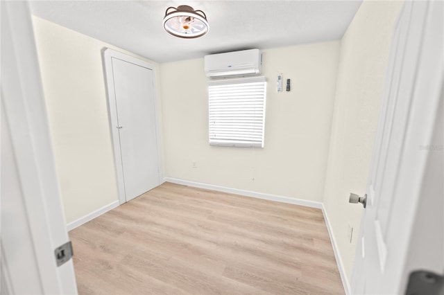 unfurnished room featuring a wall unit AC and light hardwood / wood-style floors