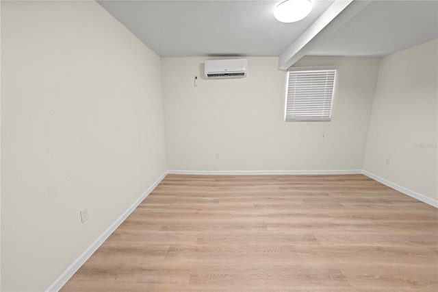 basement featuring a wall unit AC and light hardwood / wood-style floors