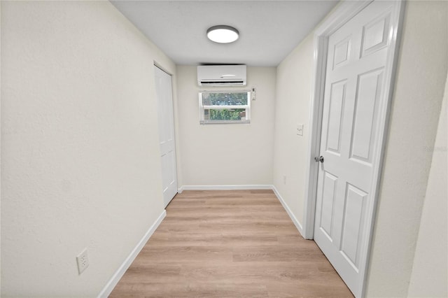 corridor with light wood-type flooring and a wall unit AC