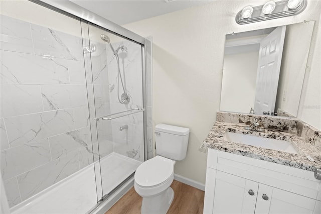 bathroom with wood-type flooring, toilet, a shower with shower door, and vanity