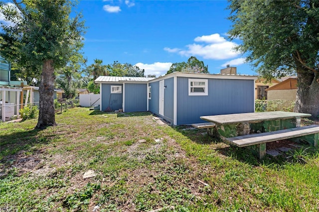 back of house with an outdoor structure and a lawn