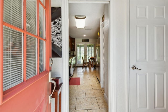 corridor with a textured ceiling and light tile patterned floors