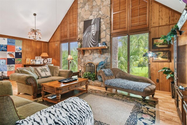 living room featuring light hardwood / wood-style floors, wooden walls, a wealth of natural light, and high vaulted ceiling