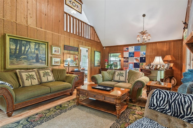 carpeted living room with high vaulted ceiling, wooden walls, and a notable chandelier