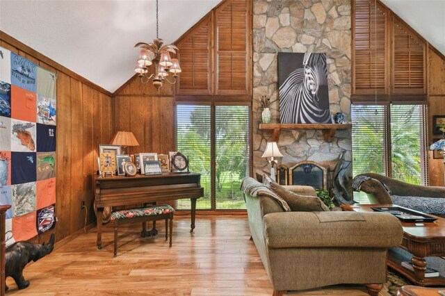 living room with high vaulted ceiling, light wood-type flooring, a stone fireplace, and wooden walls