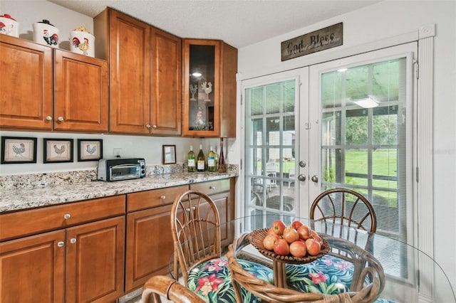 kitchen featuring a textured ceiling, light stone counters, and french doors