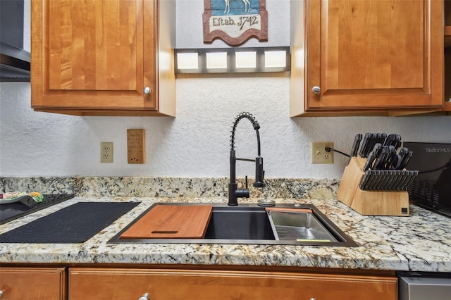 kitchen featuring ventilation hood, sink, and light stone counters