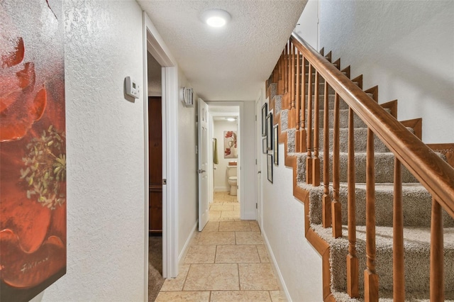 hall with light tile patterned flooring and a textured ceiling