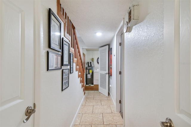 corridor with electric water heater, a textured ceiling, and light tile patterned floors