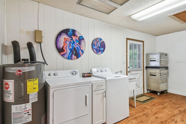 clothes washing area with electric water heater, a textured ceiling, independent washer and dryer, and light hardwood / wood-style floors