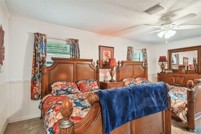 bedroom featuring a textured ceiling, ornamental molding, carpet floors, and ceiling fan